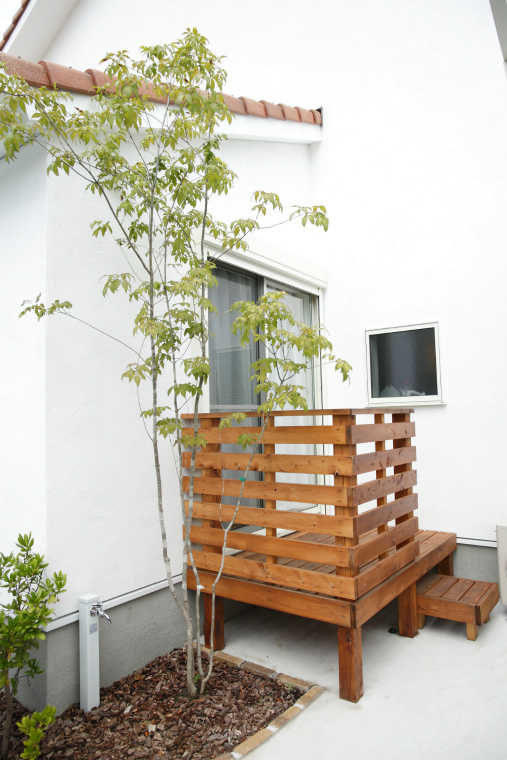外壁に映える植木とコンパクトな木製デッキ